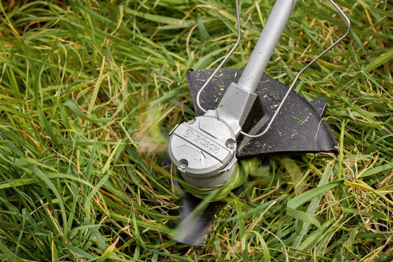 无绳割草机使用旋转刀片修剪高草。.