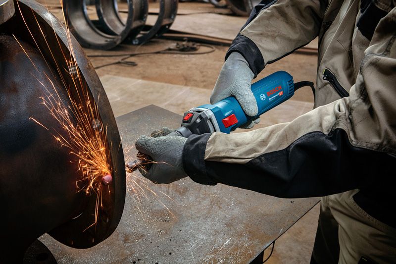 一名佩戴安全设备的人研磨金属，产生明亮的火花。.