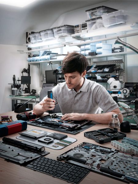 车间里，工人正在用无绳螺丝刀组装电子设备。.