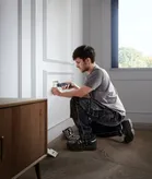 一个人用无绳螺丝刀安装电源插座盖。.