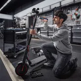 一个人跪下来，用无绳螺丝刀修理电动滑板车。.