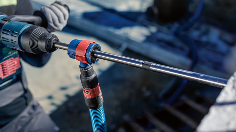 一名佩戴安全设备的人员使用旋转工具在混凝土中钻孔。