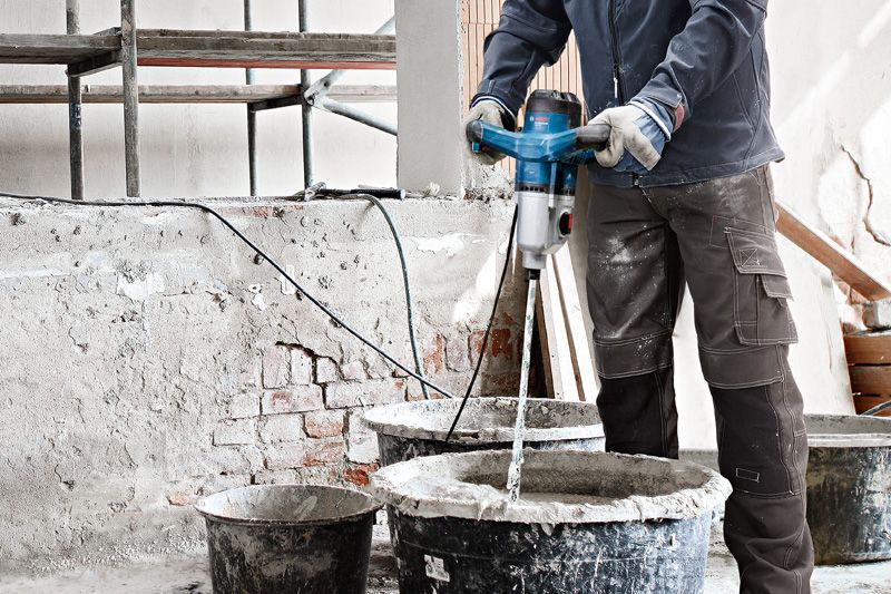 一名佩戴安全设备的人员使用搅拌装置混合建筑材料。