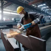 工厂里，一名佩戴安全设备的人员正在打磨钢梁，产生火花。.