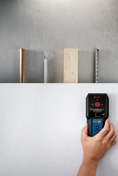 一个人使用探测器扫描墙壁以寻找金属、木材和电线。.