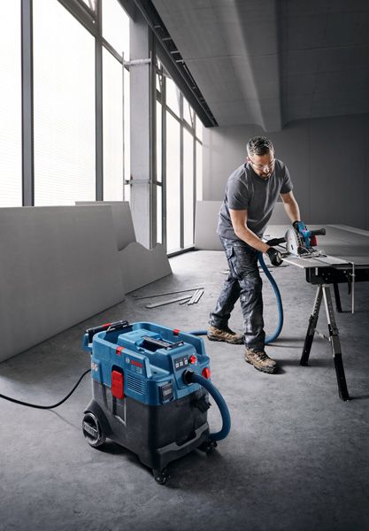 一名佩戴安全设备的人员使用多用途提取器切割支架上的木板。.