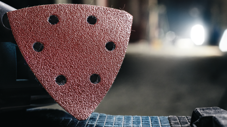 附在电动工具上的三角形砂磨垫的详细视图。