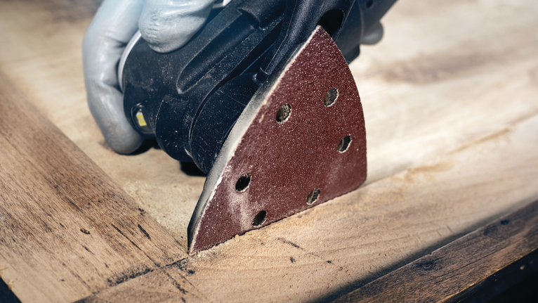 佩戴安全设备的人员使用细节打磨机打磨木质表面。