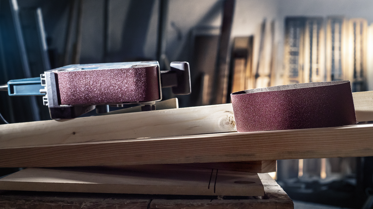 带式砂光机和砂带放置在车间的木板上。