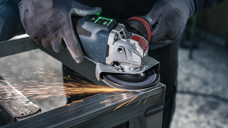 佩戴安全设备的人研磨金属，产生火花。