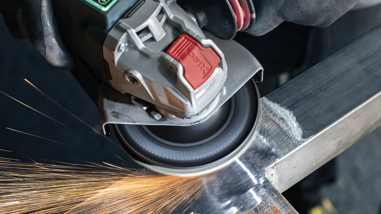 佩戴安全设备的人研磨金属，产生火花。