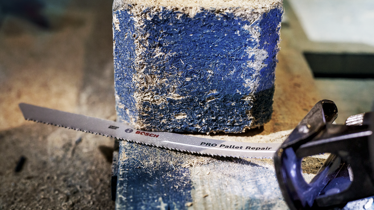 往复锯片放置在布满灰尘的木质托盘块上。