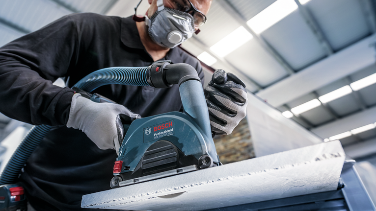 佩戴安全设备的人员使用电动工具打磨混凝土表面。