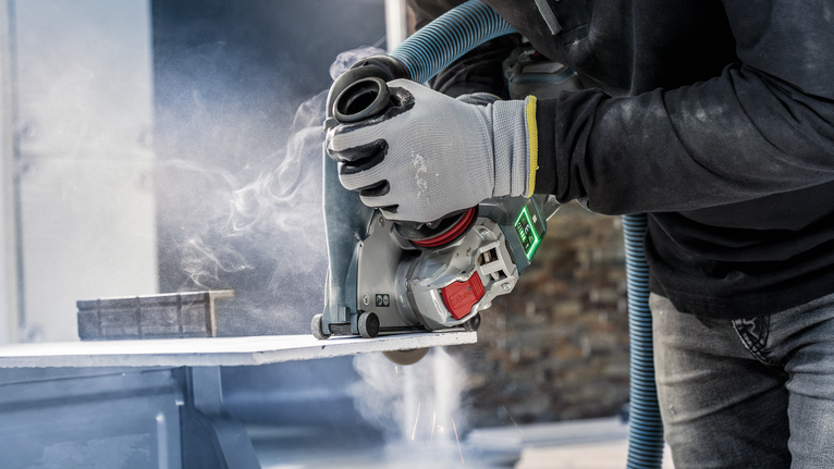 一名佩戴安全设备的人员使用动力切割机切割石板。