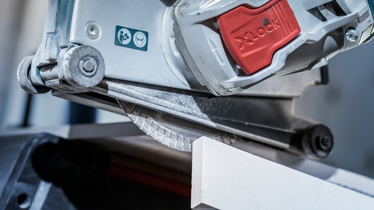 圆锯切割白色瓷砖，上面可见安全警告标签。