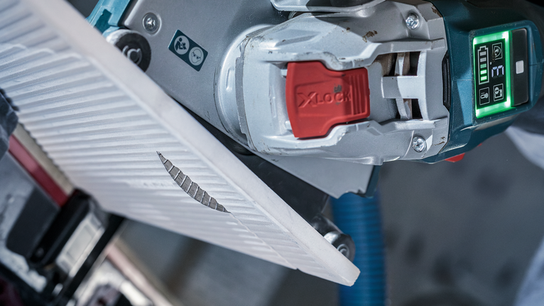 角磨机沿着标记线切割瓷砖。