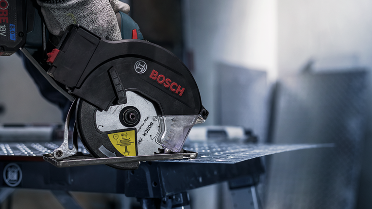 一名佩戴安全设备的人用圆锯切割金属板。