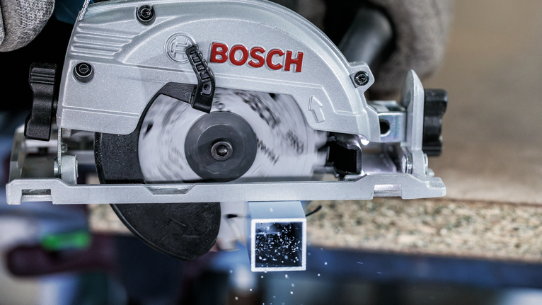 佩戴安全设备的人员使用圆锯切割金属方管。