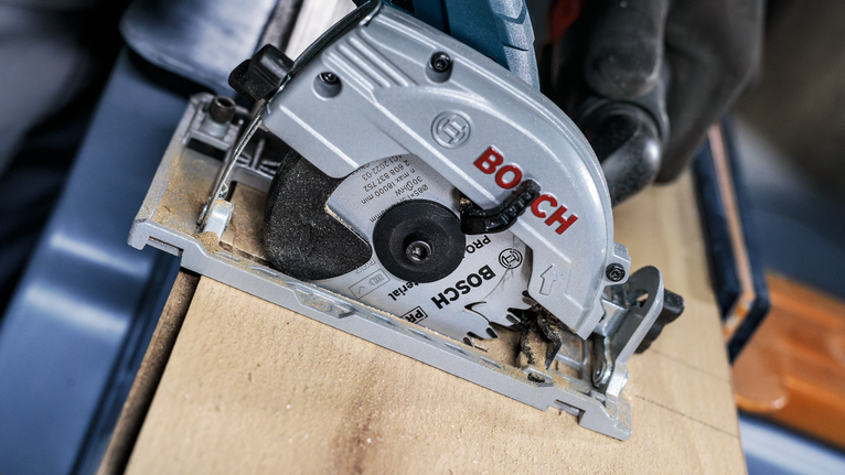 佩戴安全设备的人员使用圆锯切割木材。