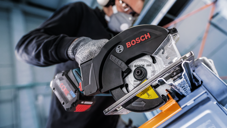 一名佩戴安全设备的人使用圆锯切割金属。