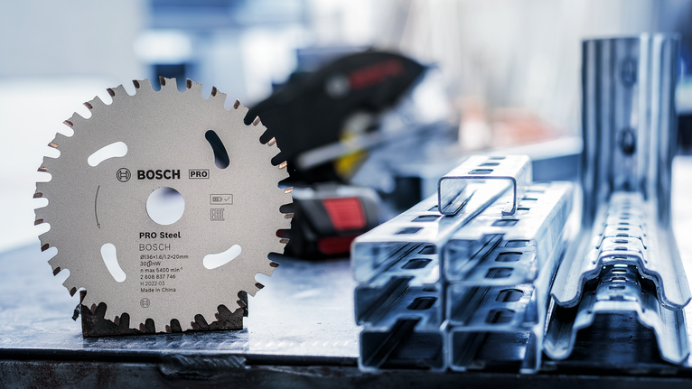 圆锯片直立在堆叠的金属梁旁边的工作台上。