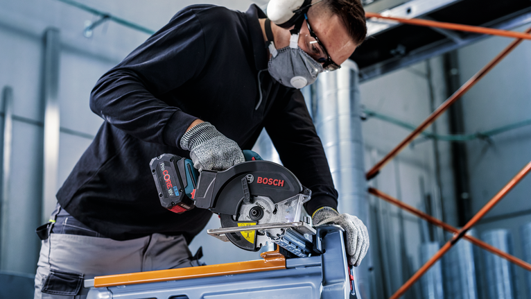 一名佩戴安全设备的人使用圆锯切割金属。