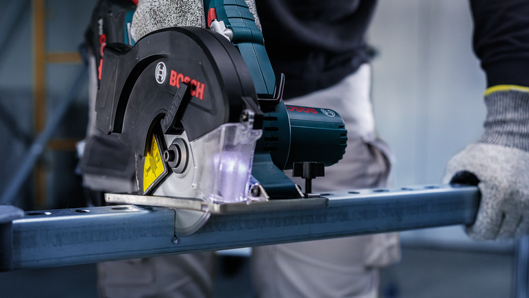 一名佩戴安全设备的人用圆锯切割金属。