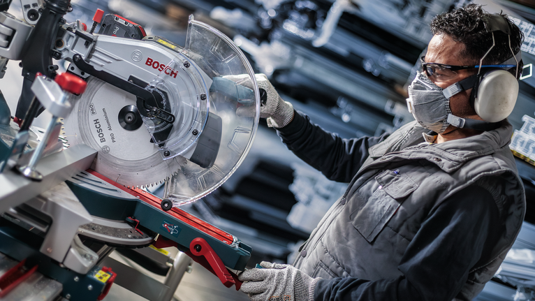 佩戴安全设备的人员在车间调整圆锯。