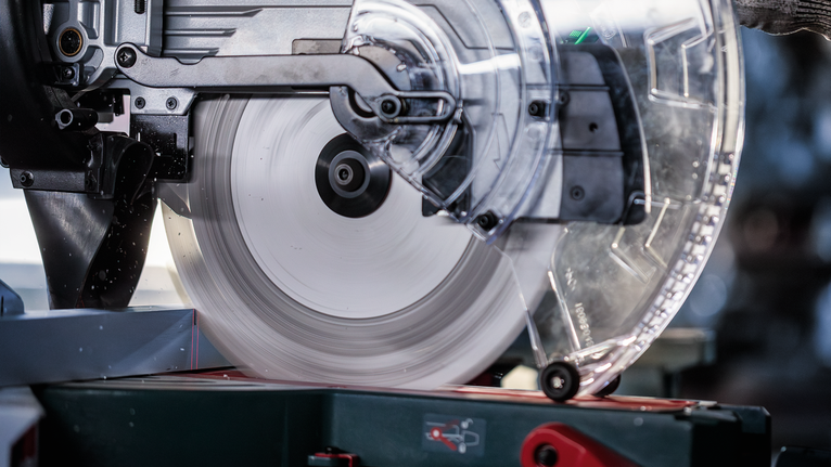 圆锯片旋转切割金属，使用时配有防护装置。