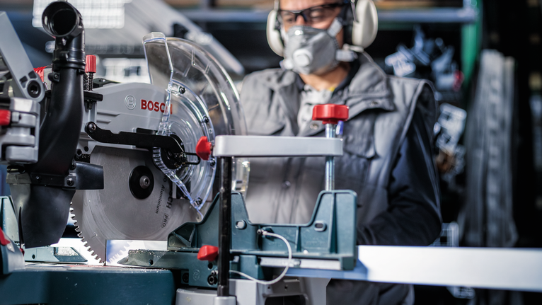 一名佩戴安全设备的人员在车间操作圆锯。
