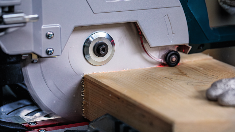 佩戴安全设备的人员用圆锯切割木板。