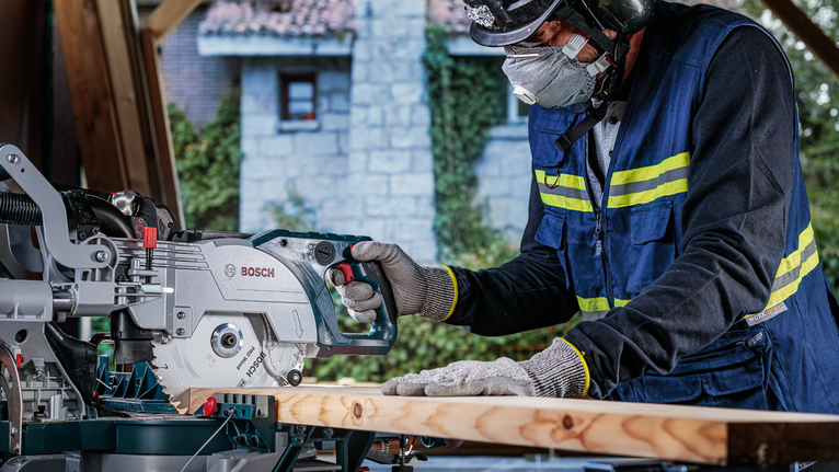 一名佩戴安全设备的人正在用电锯切割木材。
