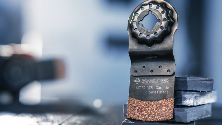 振荡多工具硬质合金刀片直立在堆叠的瓷砖上。