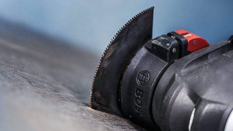 带有直刀片的振荡多功能工具可切割深色表面。