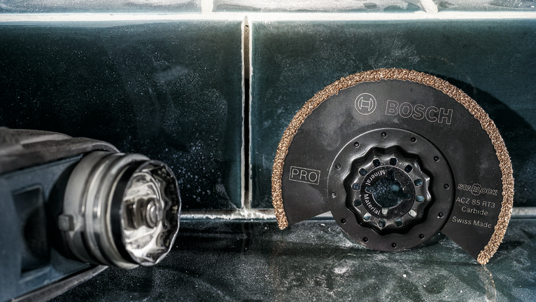 圆形硬质合金锯片放置在电动工具旁边的瓷砖表面上。