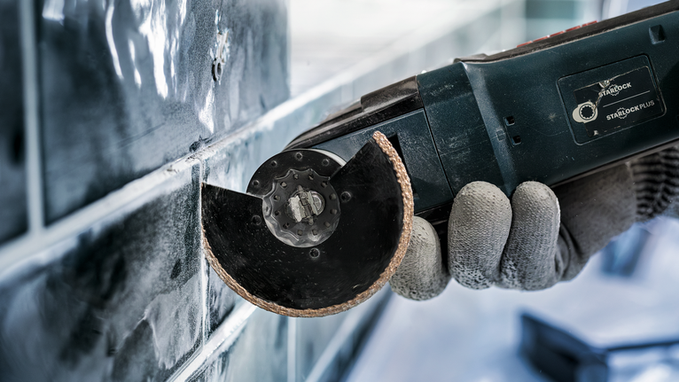 一名佩戴安全设备的人员使用电动工具切割瓷砖。