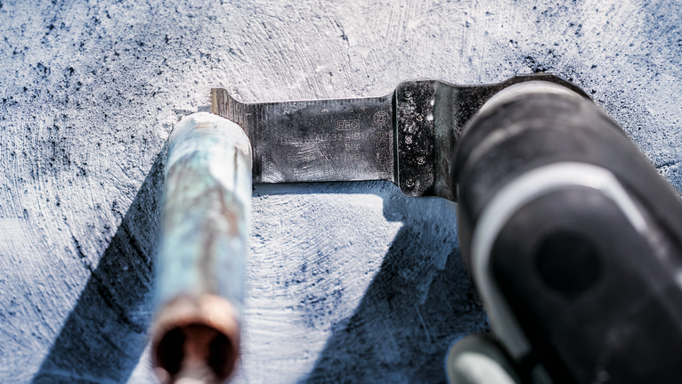 振荡工具切割混凝土表面上的金属管。