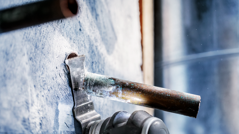 电动工具切断了从混凝土墙伸出的金属管。