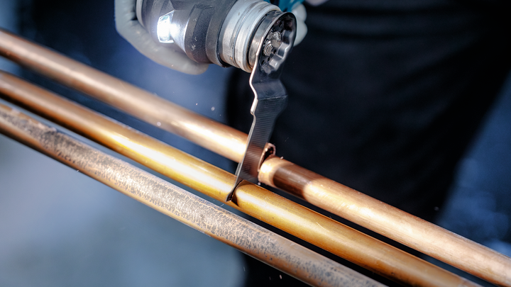 一名工人使用振荡工具切割铜管。