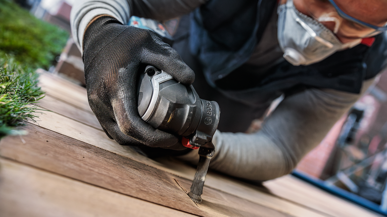 佩戴安全设备的人员使用电动工具切割木板。