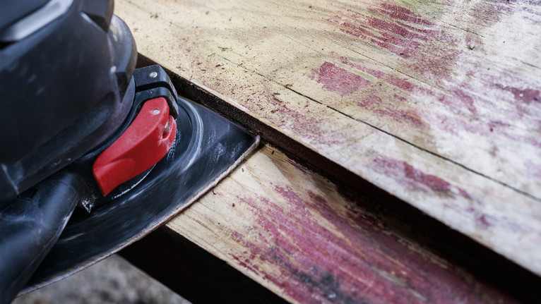 电动砂光机正在打磨一块风化的木板。