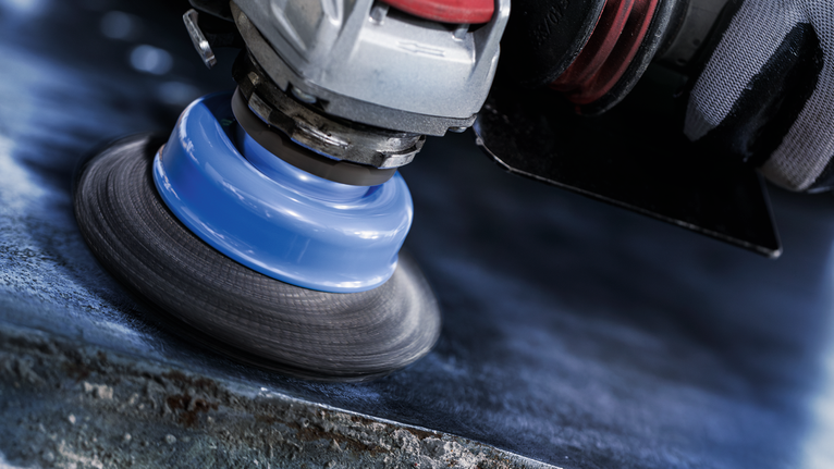 佩戴安全设备的人员使用电动工具抛光金属表面。