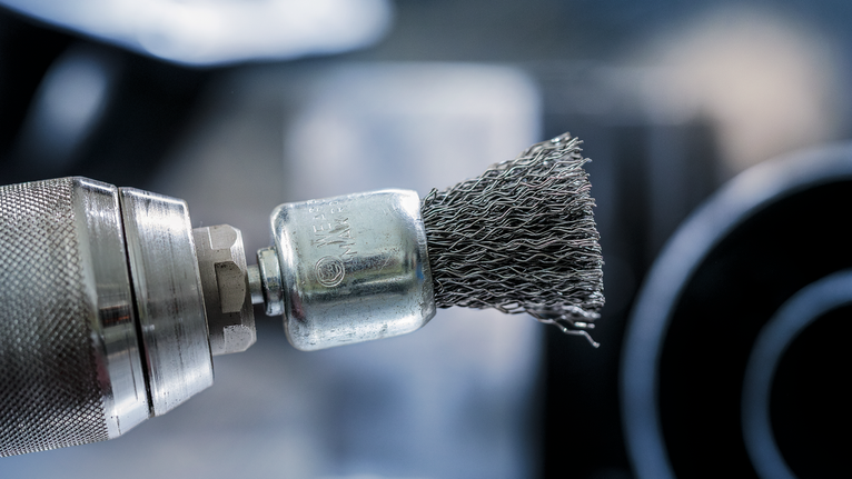 装有钢丝刷附件的电钻的特写。