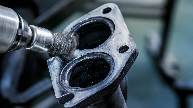 钢丝刷研磨机清洁金属发动机部件的内表面。