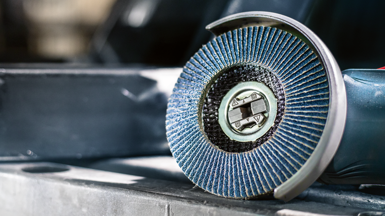 蓝色翻板磨床放置在金属表面上的特写。