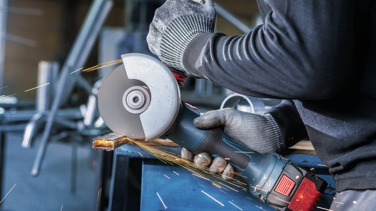 佩戴安全设备的人研磨金属，产生火花。