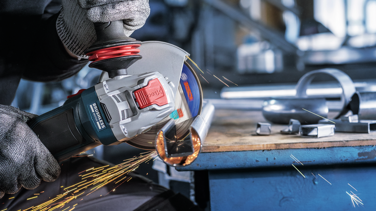 一名佩戴安全设备的人正在研磨金属管，产生火花。