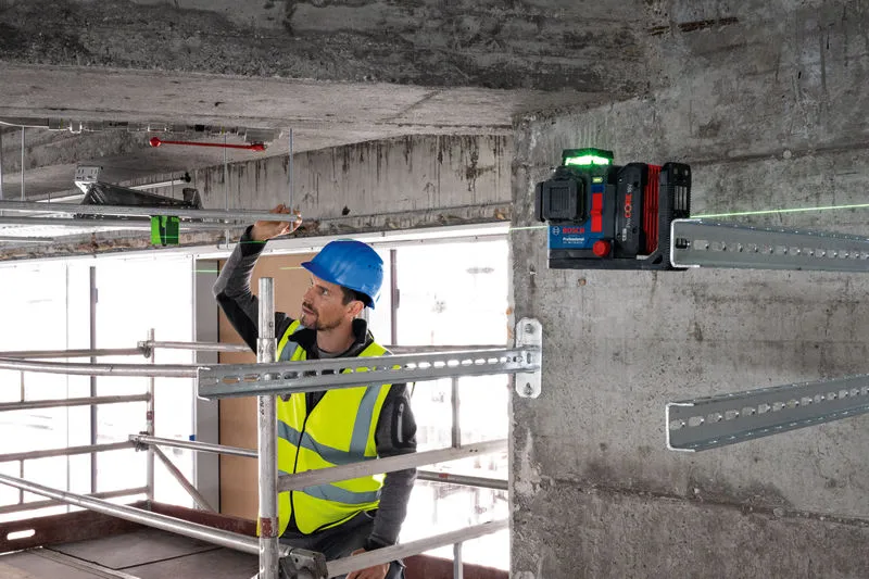 一名佩戴安全设备的人员使用激光调平工具对准金属棒。.