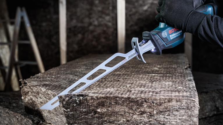 佩戴安全设备的人员使用往复锯切割绝缘材料。