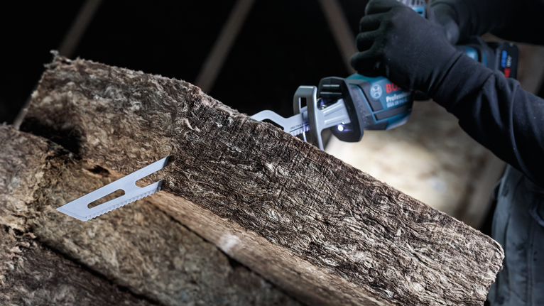 佩戴安全设备的人员使用往复锯切割厚绝缘材料。